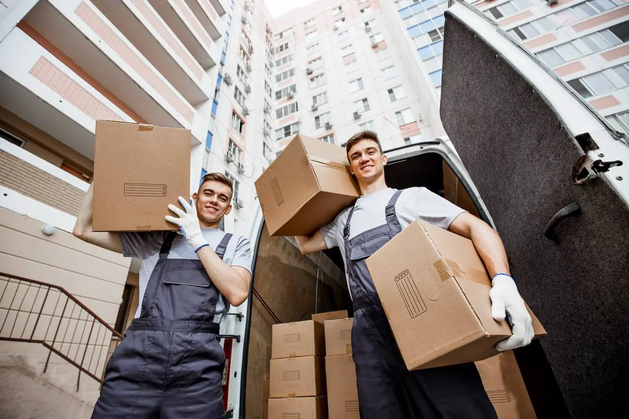 Two professional movers unloading boxes from van